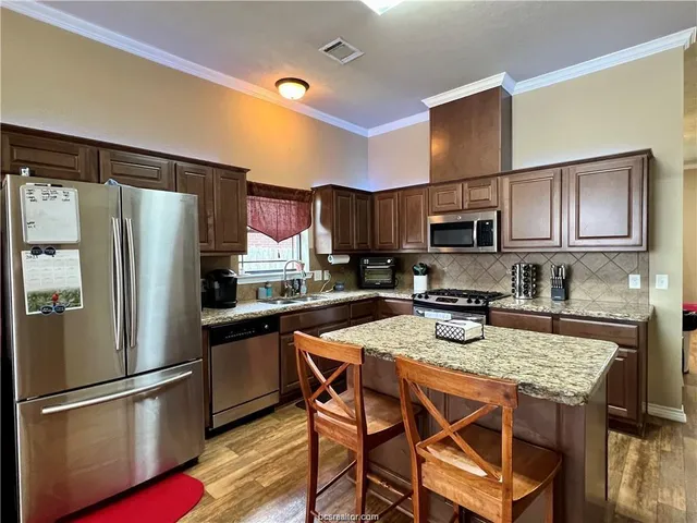 a kitchen with stainless steel appliances granite countertop a refrigerator stove microwave and sink