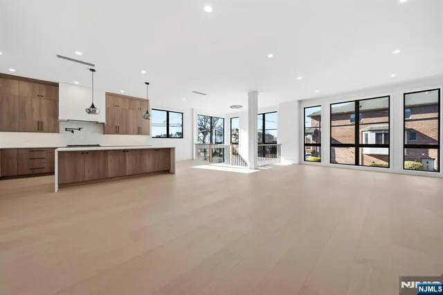 a large white kitchen with stainless steel appliances kitchen island a large counter top a stove and a refrigerator