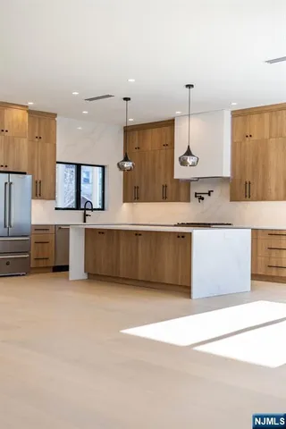 a large kitchen with a large counter top a sink stainless steel appliances and cabinets