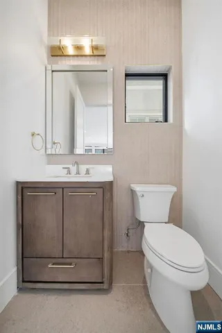 a bathroom with a toilet sink vanity and mirror