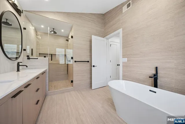 a spacious bathroom with a bathtub shower sink mirror and toilet