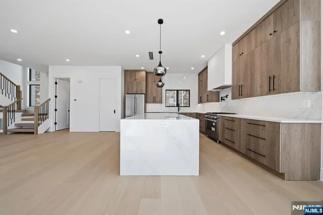a large white kitchen with a large counter top a sink stainless steel appliances and cabinets