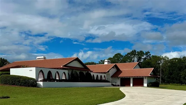 a view of a big house with a big yard plants and large trees