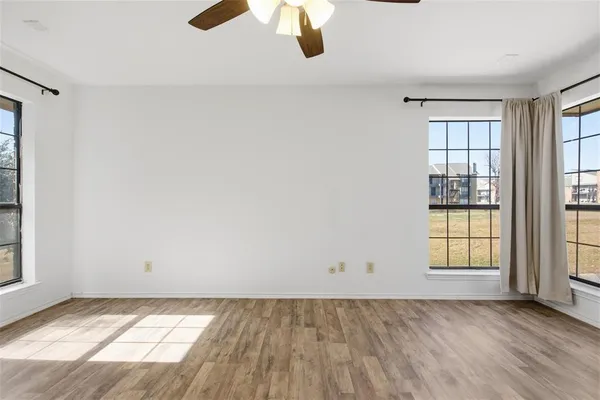 an empty room with wooden floor and windows
