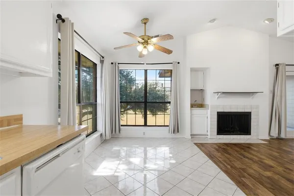 a view of an empty room with window and chandelier fan