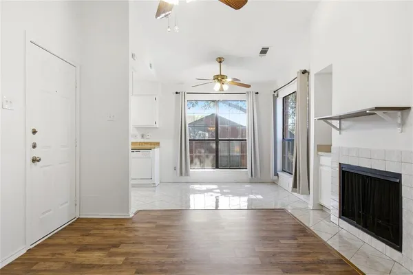 a view of an empty room with wooden floor and a fireplace