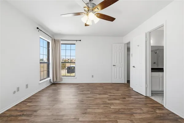 a view of an empty room with window and wooden floor