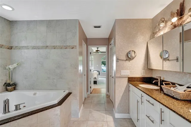 a bathroom with a granite countertop tub sink and mirror