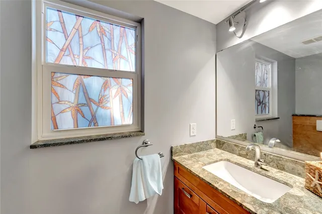 a bathroom with a granite countertop sink a mirror and a window