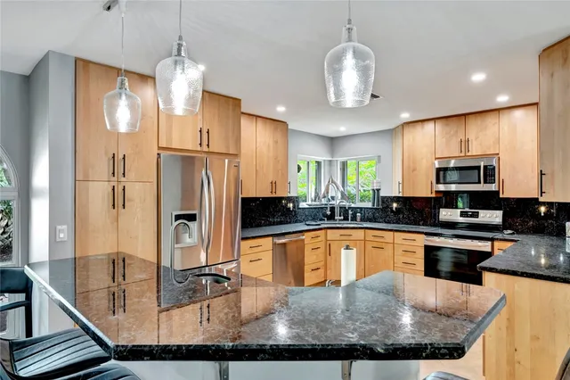 a kitchen with stainless steel appliances granite countertop a sink refrigerator and cabinets