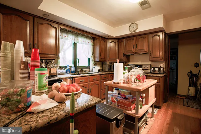 a kitchen with granite countertop lots of clutter and stainless steel appliances