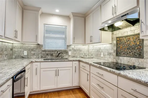 a kitchen with granite countertop stainless steel appliances white cabinets sink and dishwasher