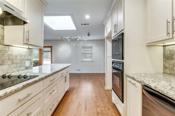 a kitchen with stainless steel appliances granite countertop a sink a stove and a wooden floors