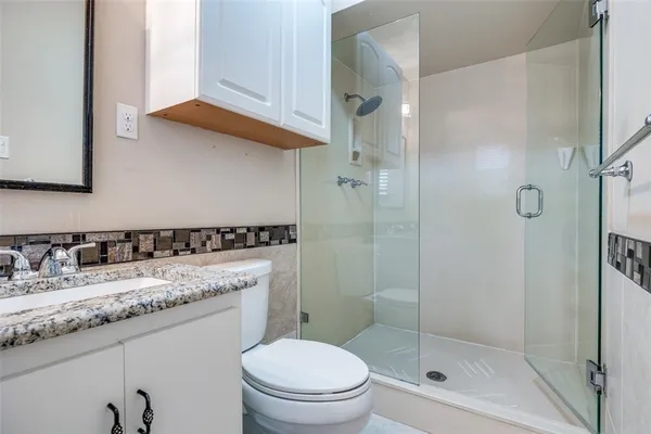 a bathroom with a granite countertop sink a mirror and a shower