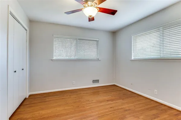 a view of an empty room with window and a chandelier fan