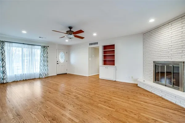 a view of an empty room with a window and a kitchen