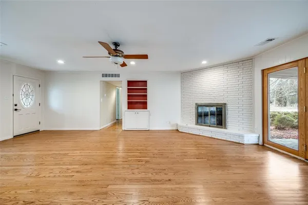a view of an empty room with window and wooden floor