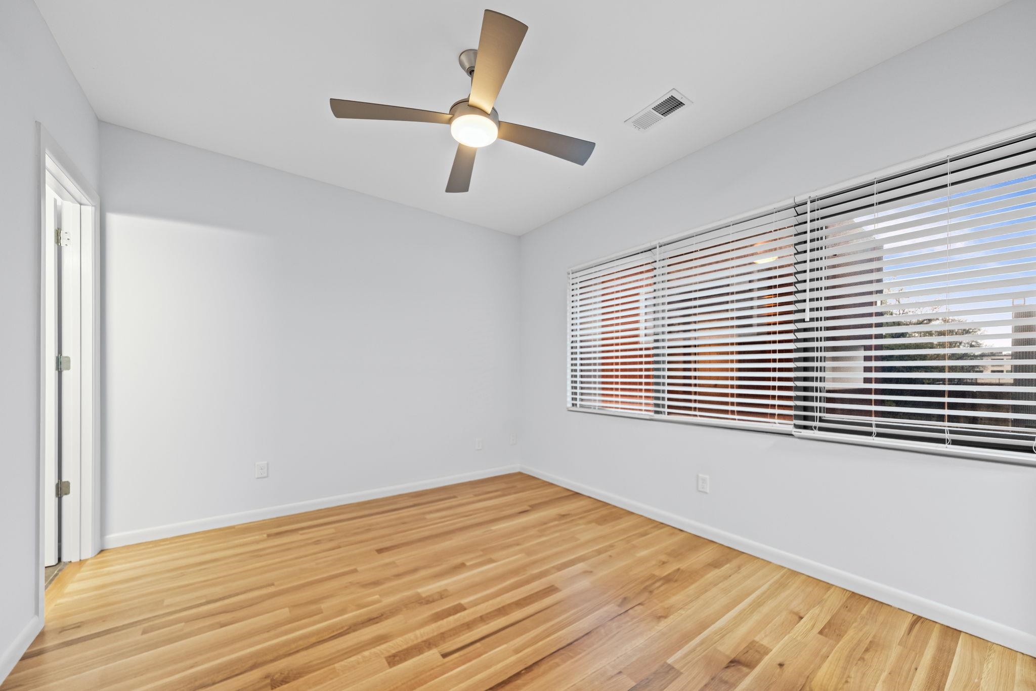 448 Tennessee Street Memphis, TN 38103 - Photo 15 of 39 Room featuring wood-finish flooring, a contemporary ceiling fan with integrated lighting, and multiple windows with horizontal blinds
