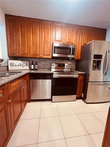 a kitchen with stainless steel appliances granite countertop a stove a sink dishwasher and a refrigerator