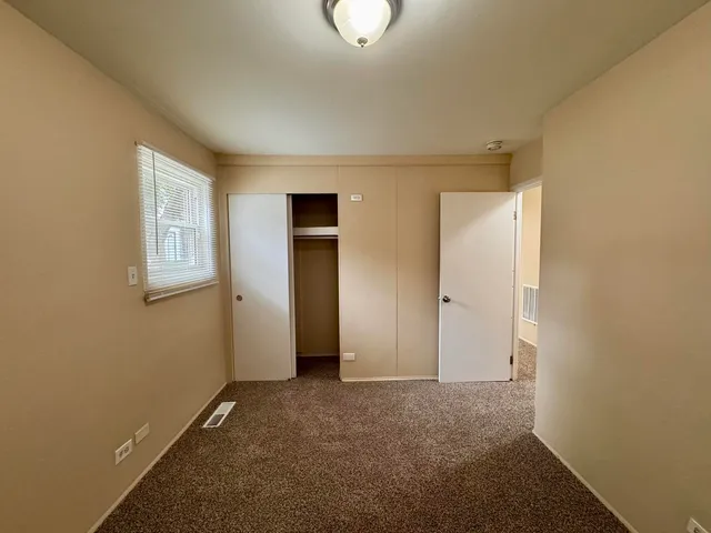 a view of an empty room with windows and closet
