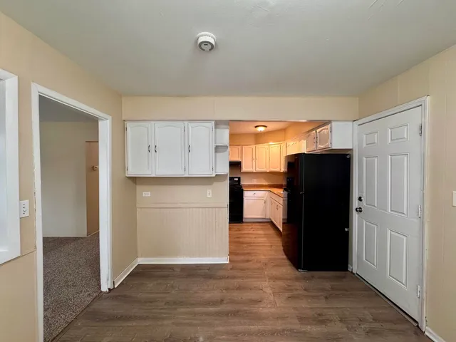 a view of kitchen with refrigerator and wooden cabinets