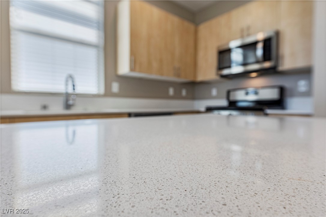 11238 Essence Point Avenue, Unit 201 Las Vegas, NV 89135 - Photo 14 of 52 Kitchen with stainless steel microwave, stove, light brown cabinets, light countertops, and modern cabinets