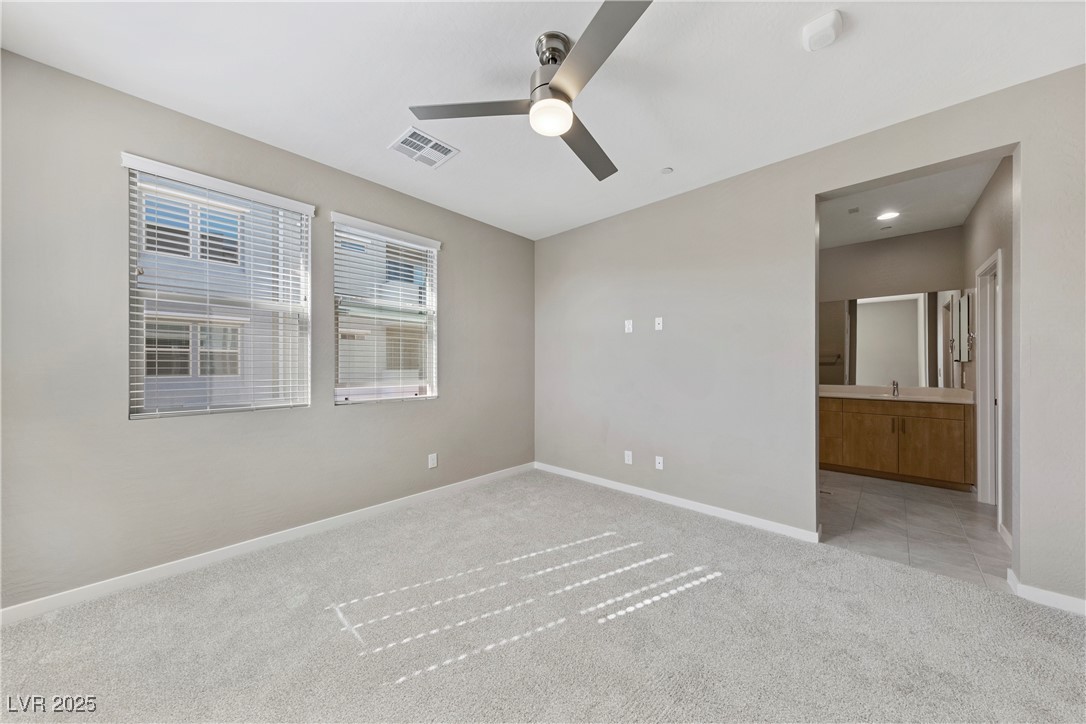 11238 Essence Point Avenue, Unit 201 Las Vegas, NV 89135 - Photo 18 of 52 Unfurnished bedroom featuring light colored carpet, ceiling fan, and ensuite bathroom
