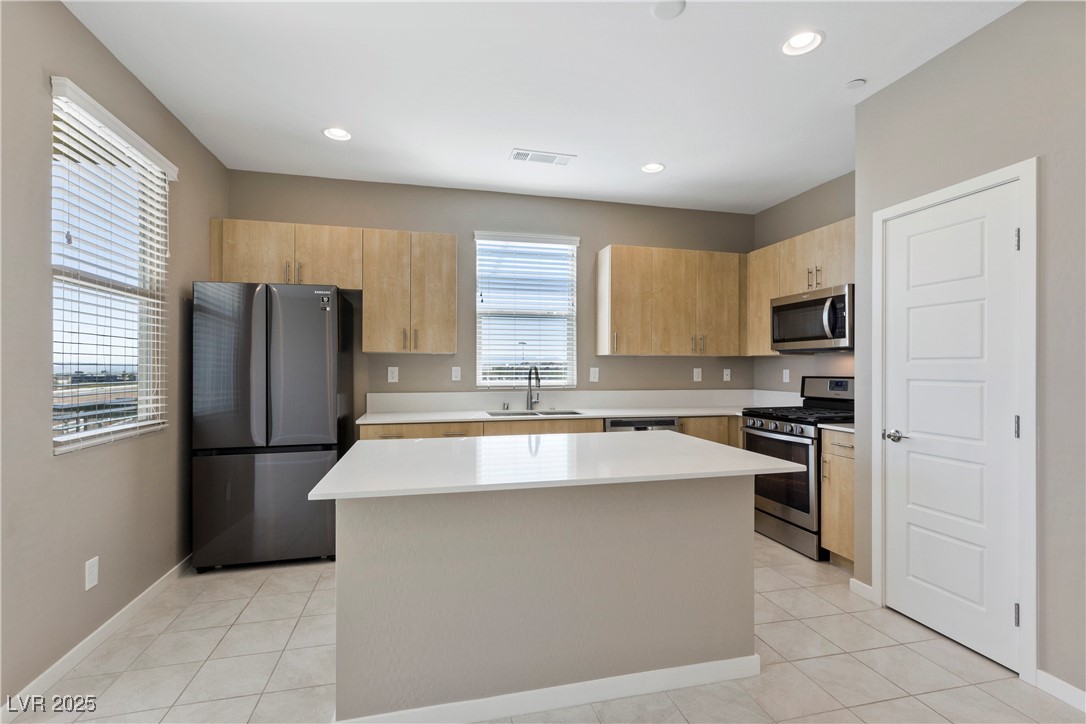 11238 Essence Point Avenue, Unit 201 Las Vegas, NV 89135 - Photo 2 of 52 Kitchen with light brown cabinetry, stainless steel appliances, light tile patterned flooring, a center island, and modern cabinets