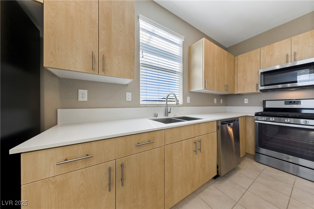 11238 Essence Point Avenue, Unit 201 Las Vegas, NV 89135 - Photo 3 of 52 Kitchen with light brown cabinets, appliances with stainless steel finishes, light tile patterned floors, and light stone countertops