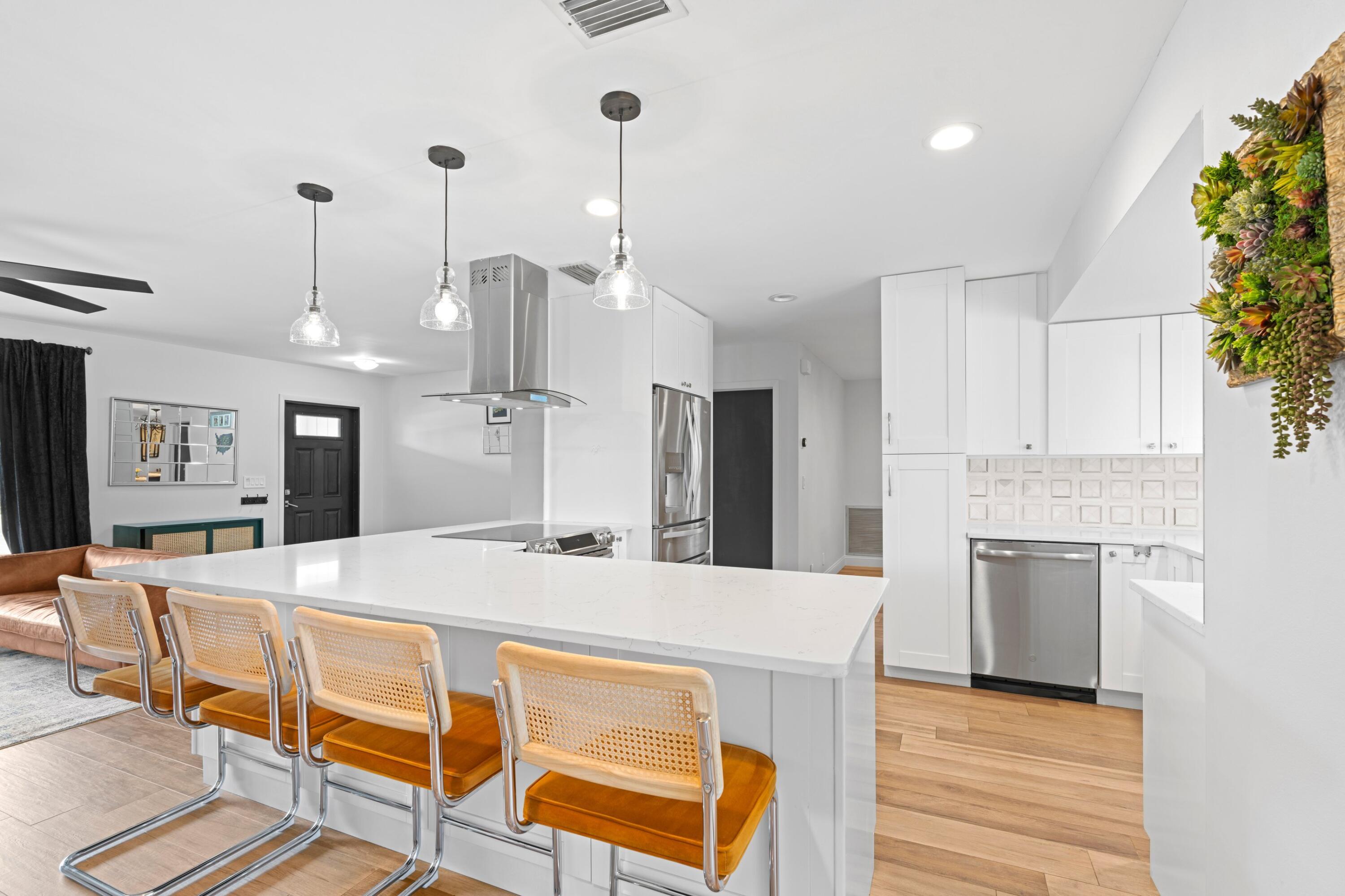 1039 Northwest 8th Street Boca Raton, FL 33486 - Photo 2 of 17 a large kitchen with kitchen island a large counter top space a sink stainless steel appliances and cabinets