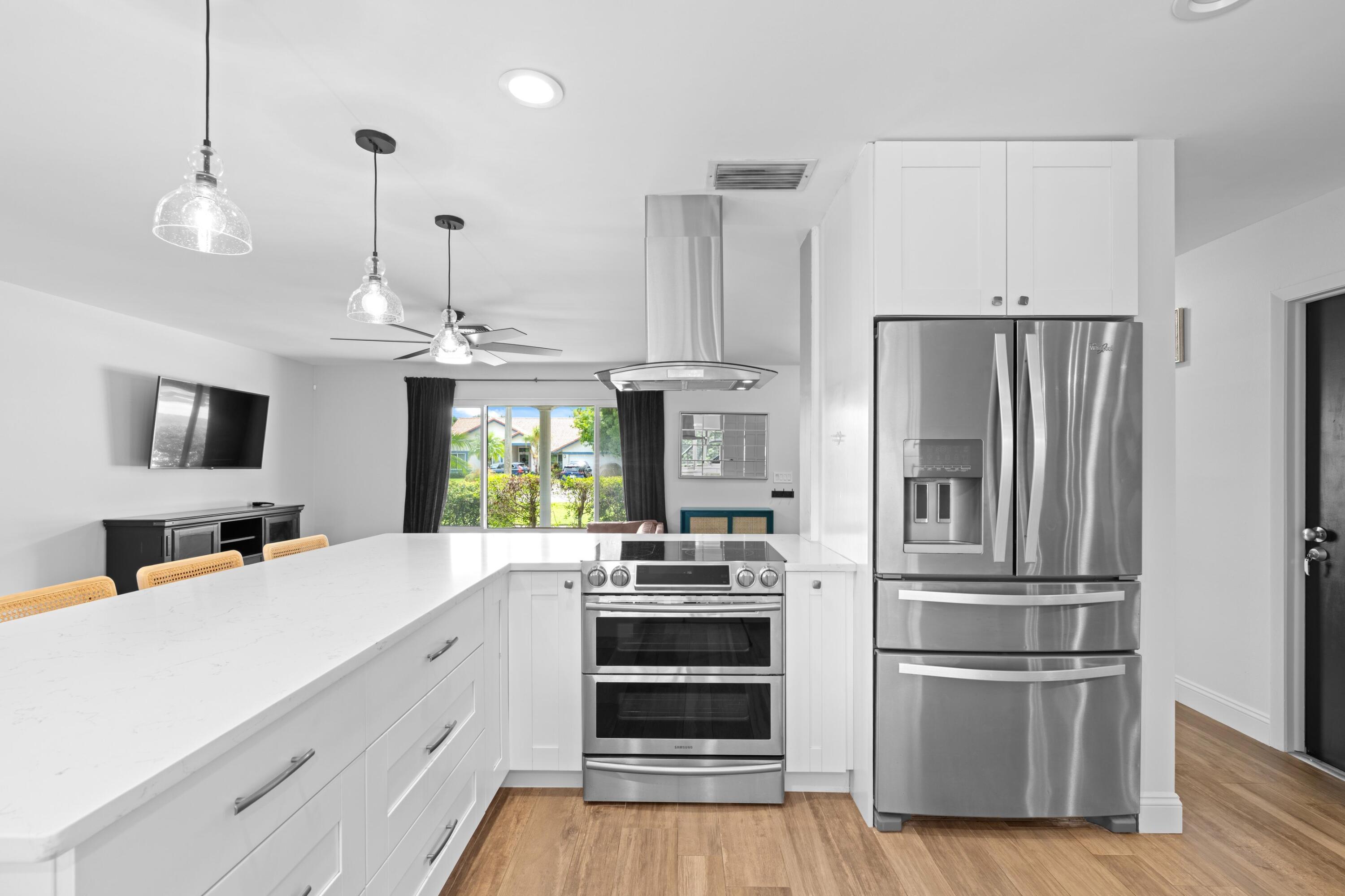 1039 Northwest 8th Street Boca Raton, FL 33486 - Photo 4 of 17 a kitchen with kitchen island a counter top a sink and stainless steel appliances
