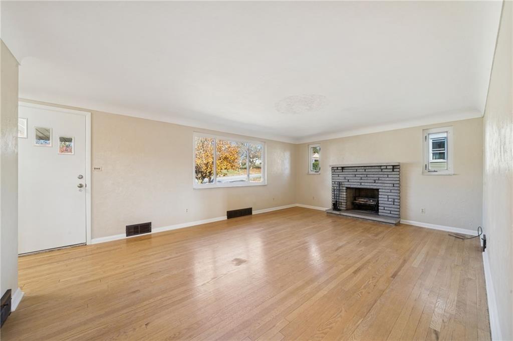 421 Robbins Station Road Irwin, PA 15642 - Photo 3 of 33 an empty room with wooden floor fireplace and windows