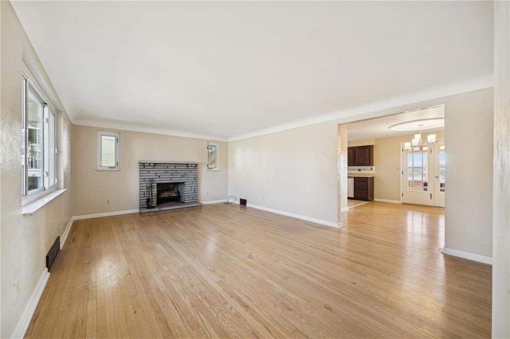 421 Robbins Station Road Irwin, PA 15642 - Photo 6 of 33 an empty room with wooden floor fireplace and windows