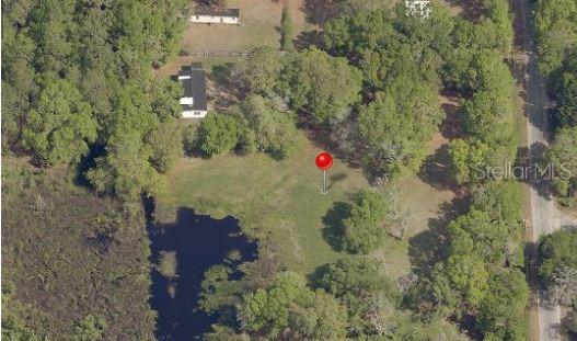 an aerial view of residential house with outdoor space and trees all around