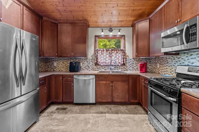 a kitchen with stainless steel appliances granite countertop a stove a sink and a refrigerator