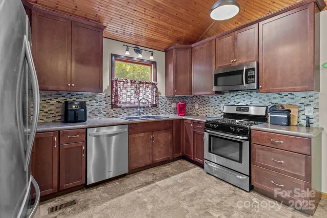 a kitchen with stainless steel appliances granite countertop wooden cabinets stove top oven and sink