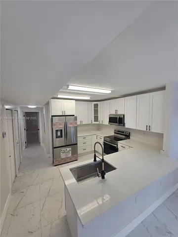 a view of a kitchen with a sink and a refrigerator