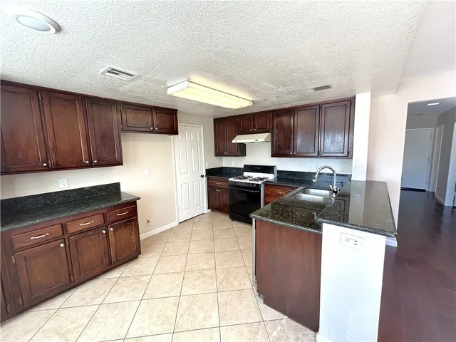a kitchen with stainless steel appliances granite countertop a stove a sink and a microwave