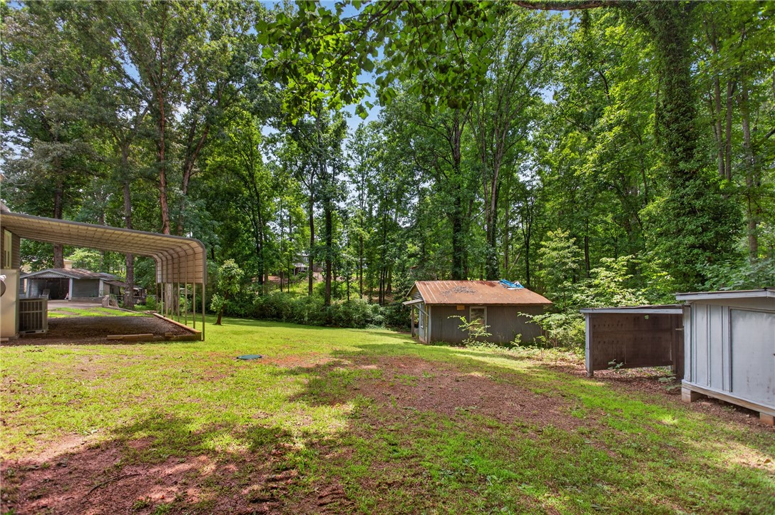 230 Dickard Road Seneca, SC 29672 - Photo 24 of 25 A spacious yard with verdant surroundings, offering an outdoor shelter and two outbuildings amidst the trees.