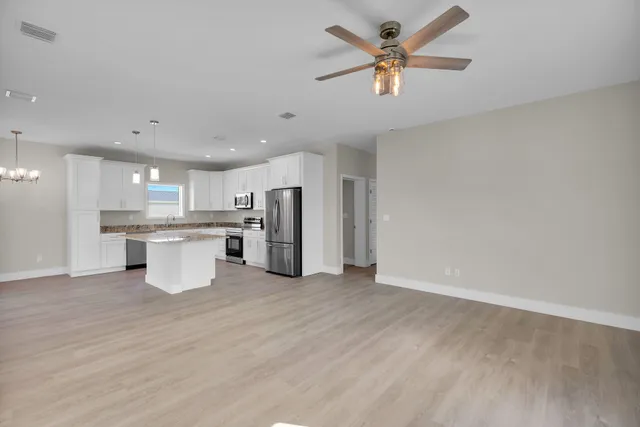 an empty room with windows and ceiling fan