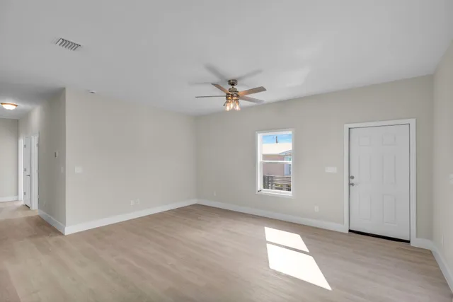 an empty room with windows and fan