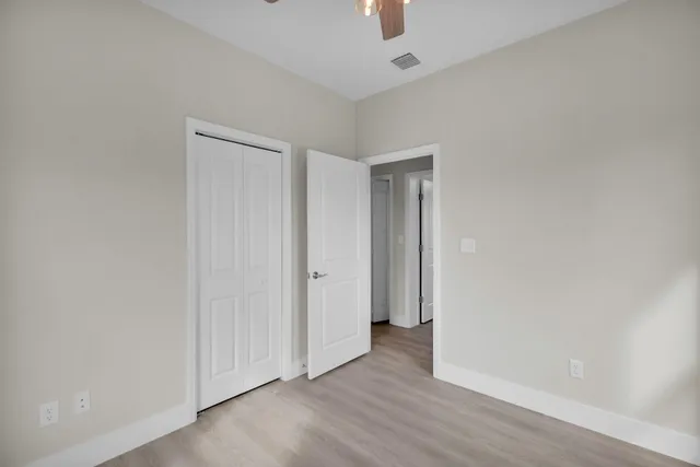 an empty room with a window and a chandelier fan