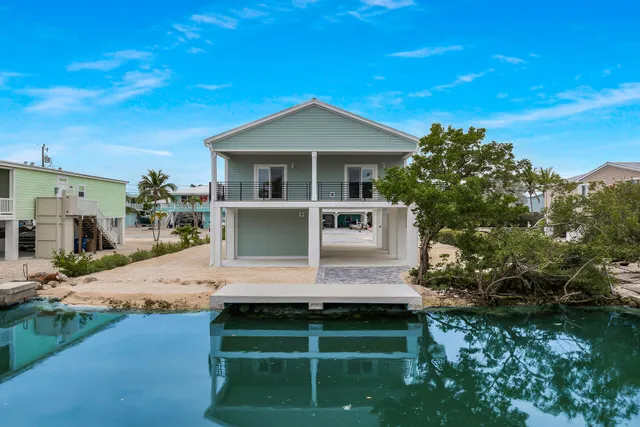 a front view of a house with a garden and lake view