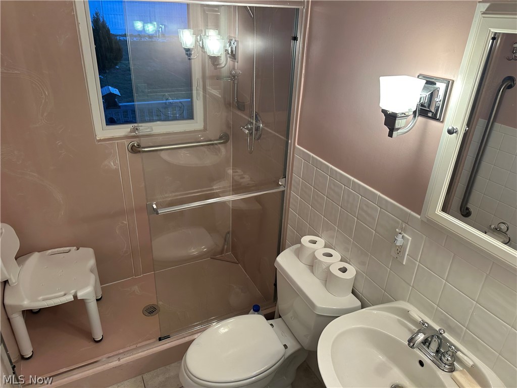 3192 Mogadore Road Akron, OH 44312 - Photo 23 of 43 First Floor Bathroom featuring tile walls, a stall shower, and a wainscoted wall