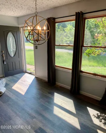 a view of an empty room with wooden floor and fan