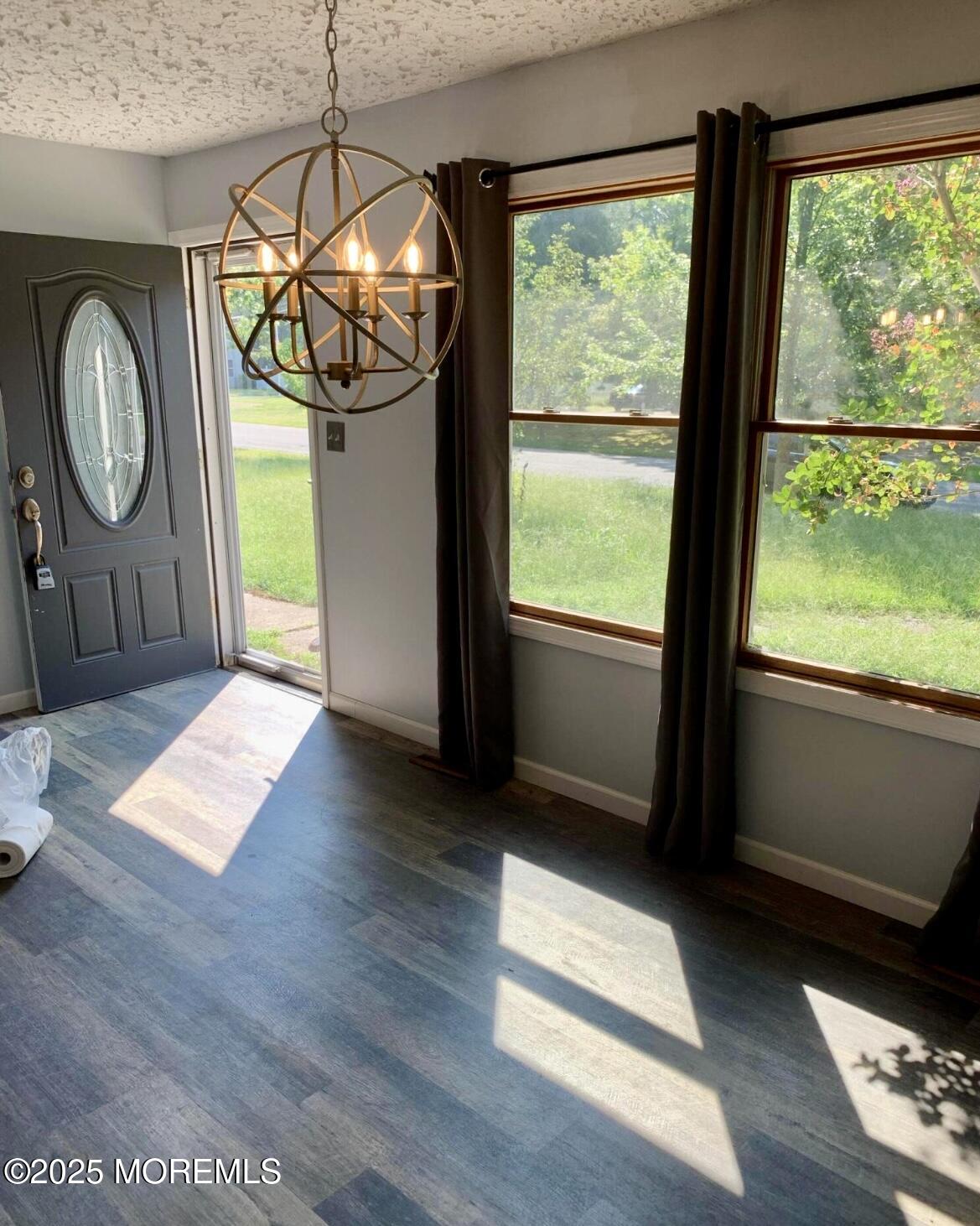 a view of an empty room with wooden floor and fan
