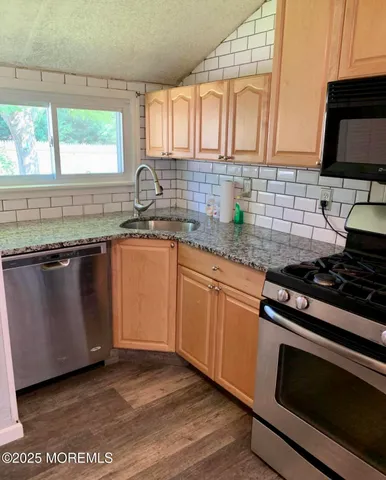 a kitchen with granite countertop a sink stainless steel appliances and cabinets