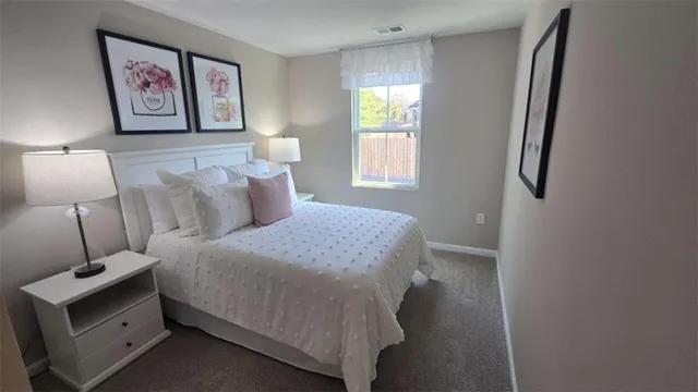 a bedroom with a bed and a lamp on dresser