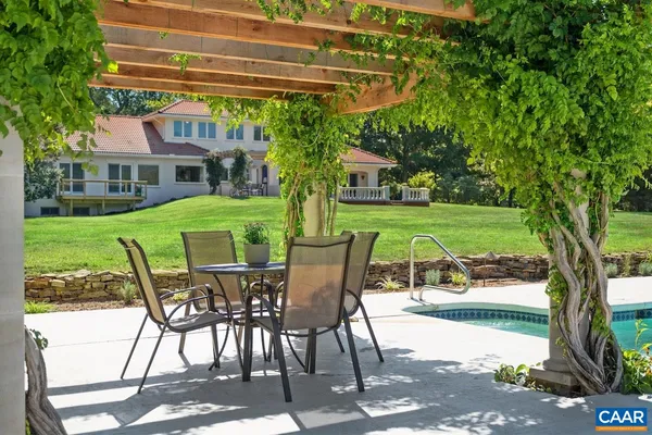 a view of swimming pool with large trees and a fence