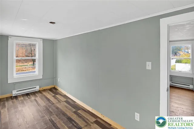 a view of an empty room with window and wooden floor